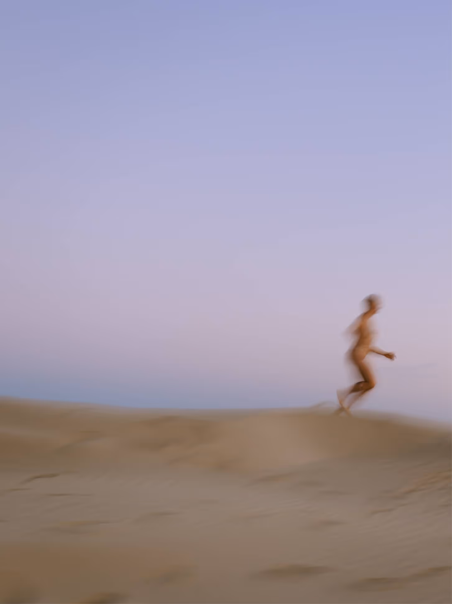Dreamy blurry photo of a person running on a beach, evoking movement, breaking free, and ongoing cycles.
